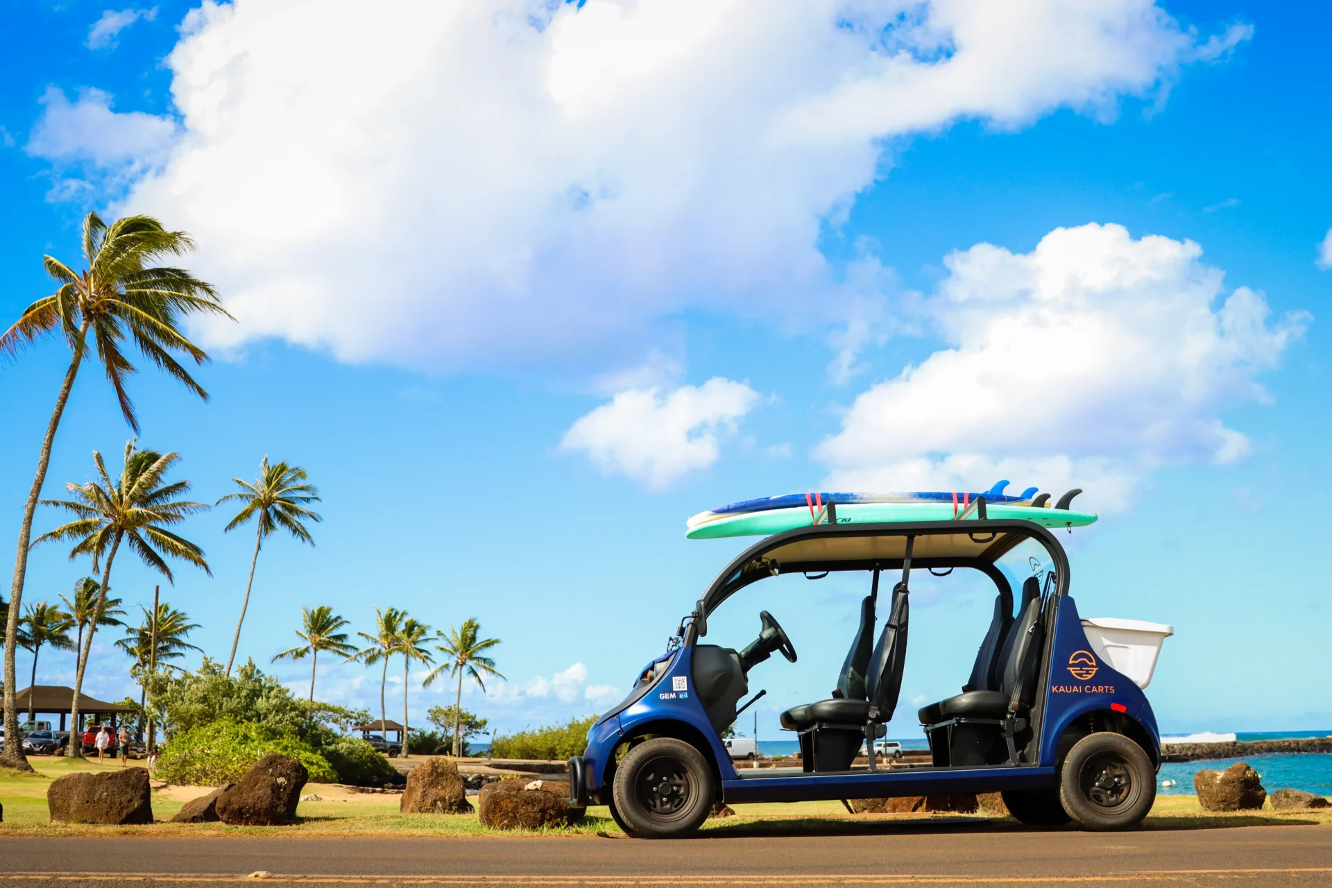 A blue car with surfboards on top of it.