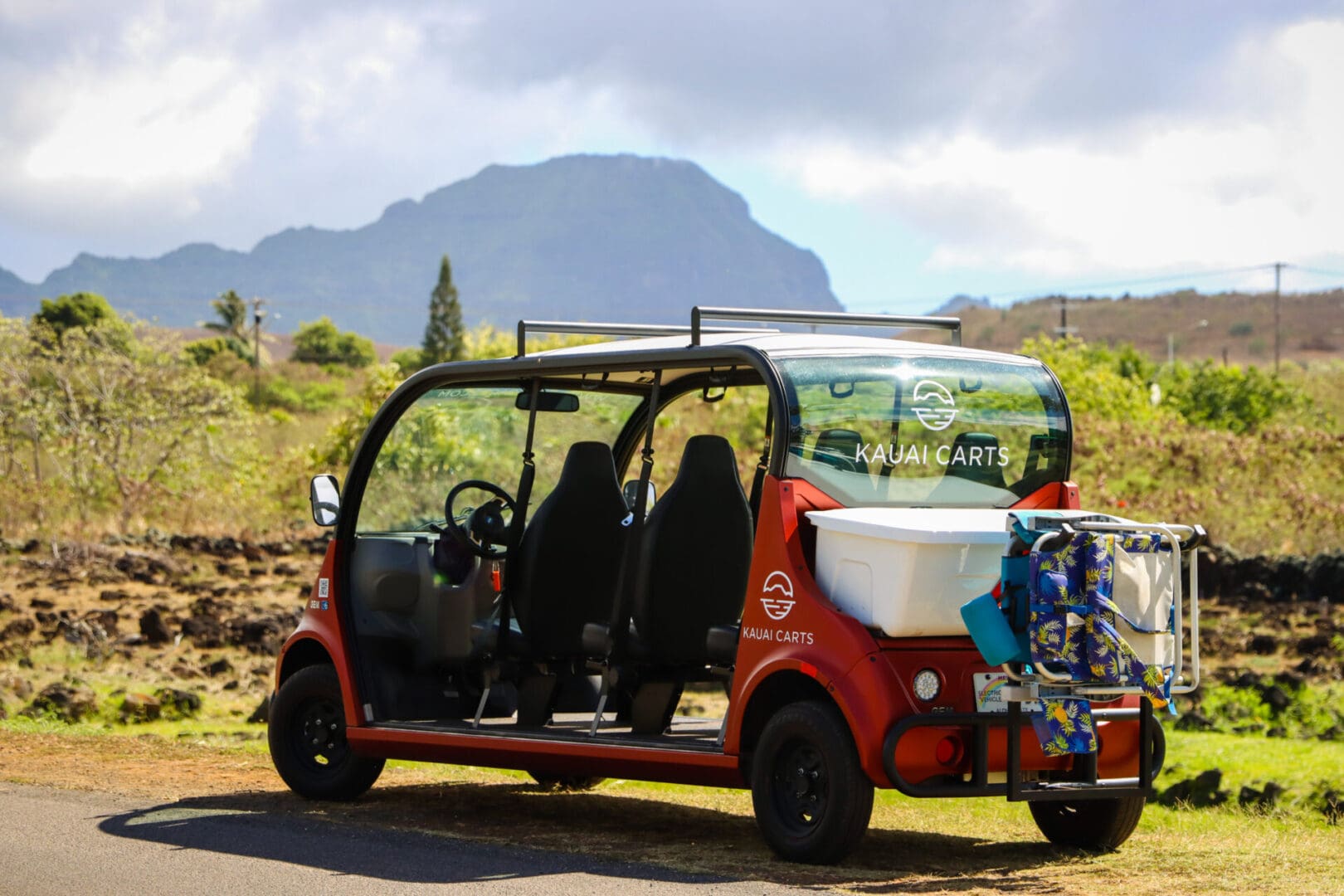 A red car with four seats and a mountain in the background.