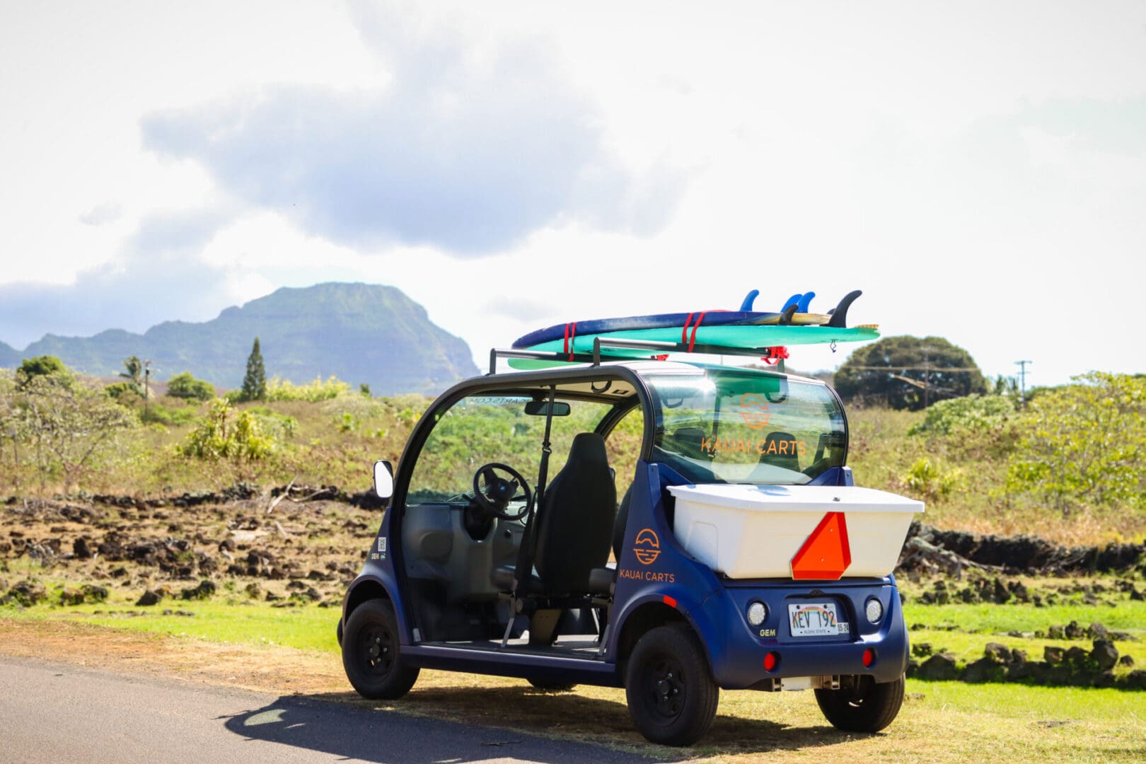 A small blue car with surfboards on top of it.